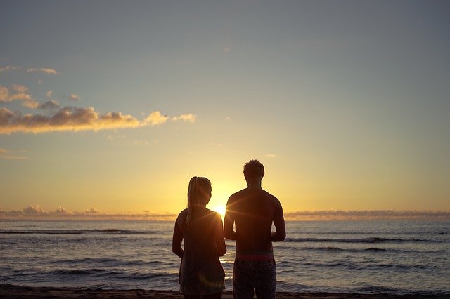 海岸で夕日背景のカップルシルエット