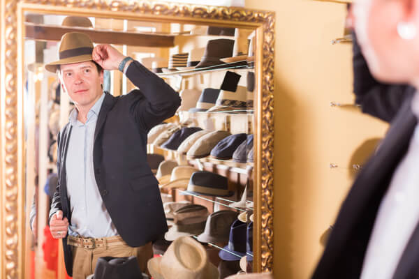 帽子店でハットをかぶって鏡を確認する外国人男性
