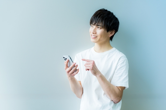 スマホを指さして遠くを見る男性