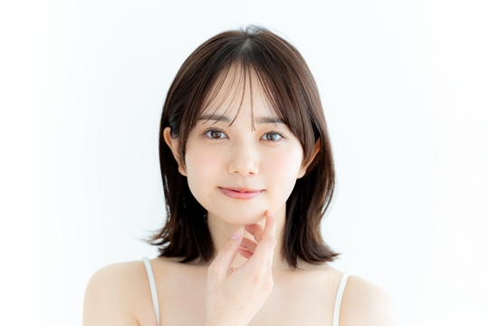右手で顎に手を当てこちらを見る女性