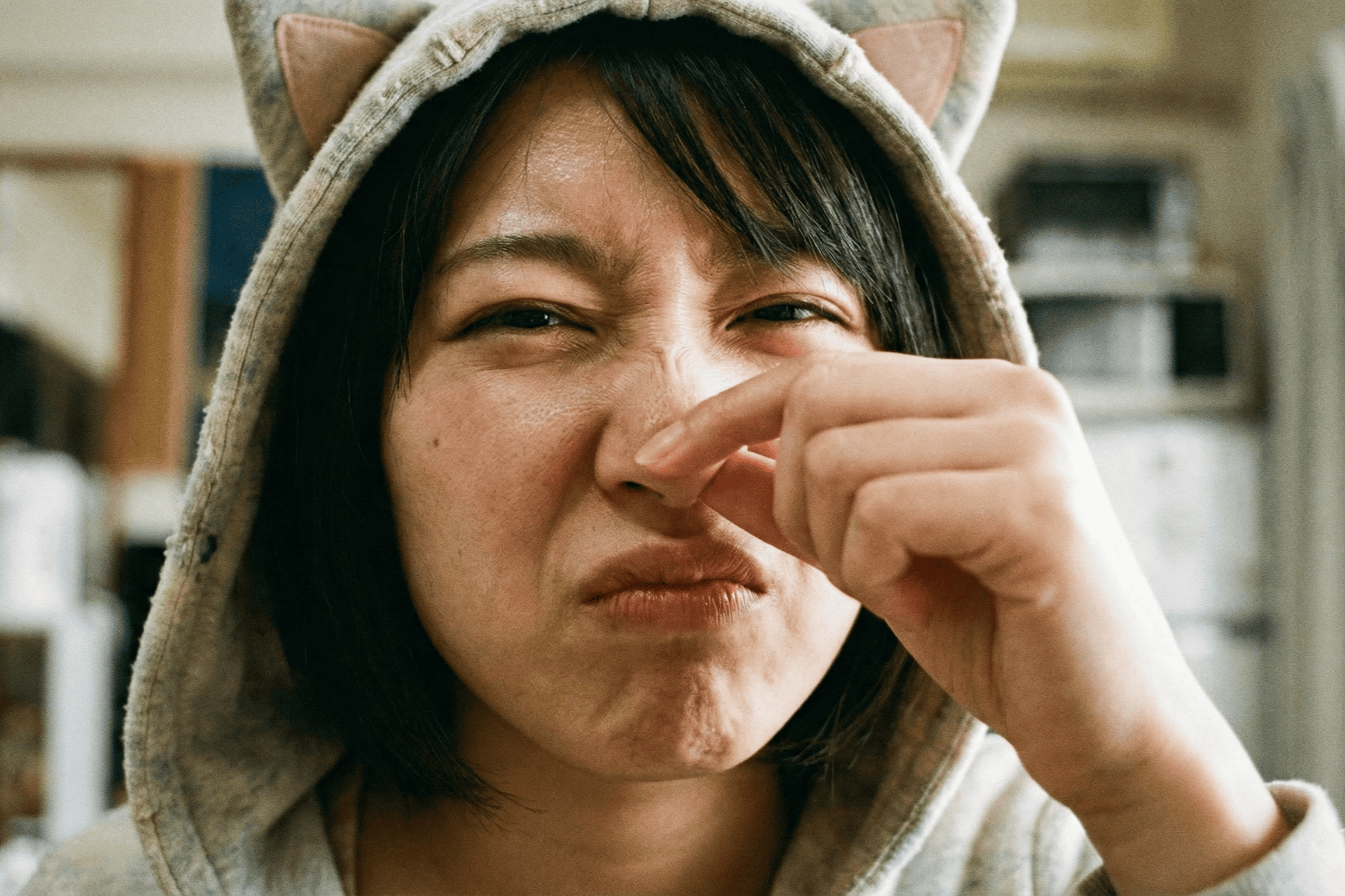 猫耳フードを被った鼻をつまむ女性